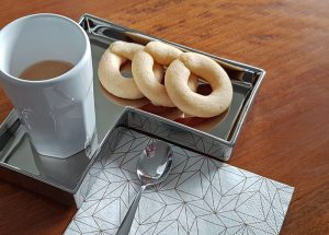Bussola - venezianische Kekse nach Original-Rezept liegen als Kringel neben einem Espresso, angerichtet auf Silberteller mit Serviette